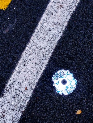 Un CD rotto, "Nevermind" dei Nirvana, sull'asfalto